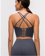 Woman wearing a dark gray sports bra and leggings set on a white background