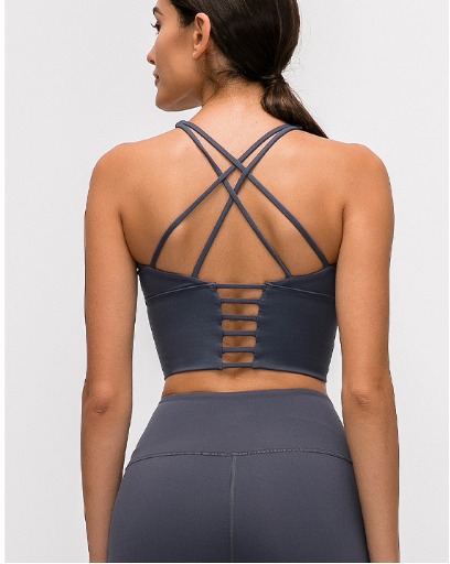 Woman wearing a dark gray sports bra and leggings set on a white background